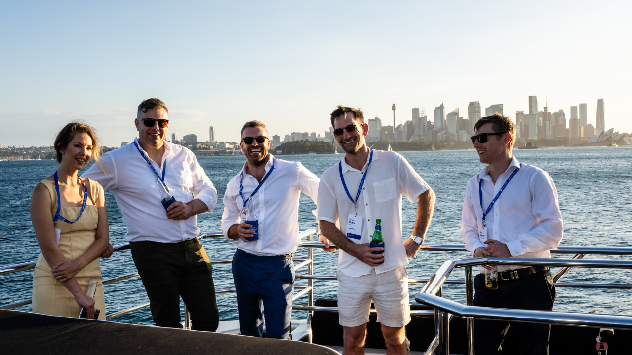 Five people standing against yacht barrier with Sydney's sky line in the background